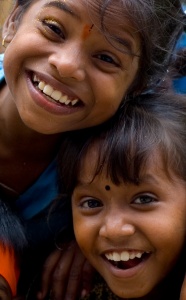 Foto i närbild på två glada barn med stora leenden, med huvudena mot varandra.